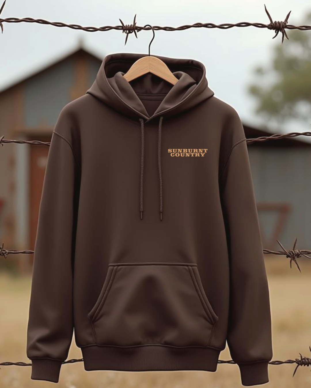 Sunburnt Country Clothing brown hoodie with text on the front hanging on a barbed wire fence