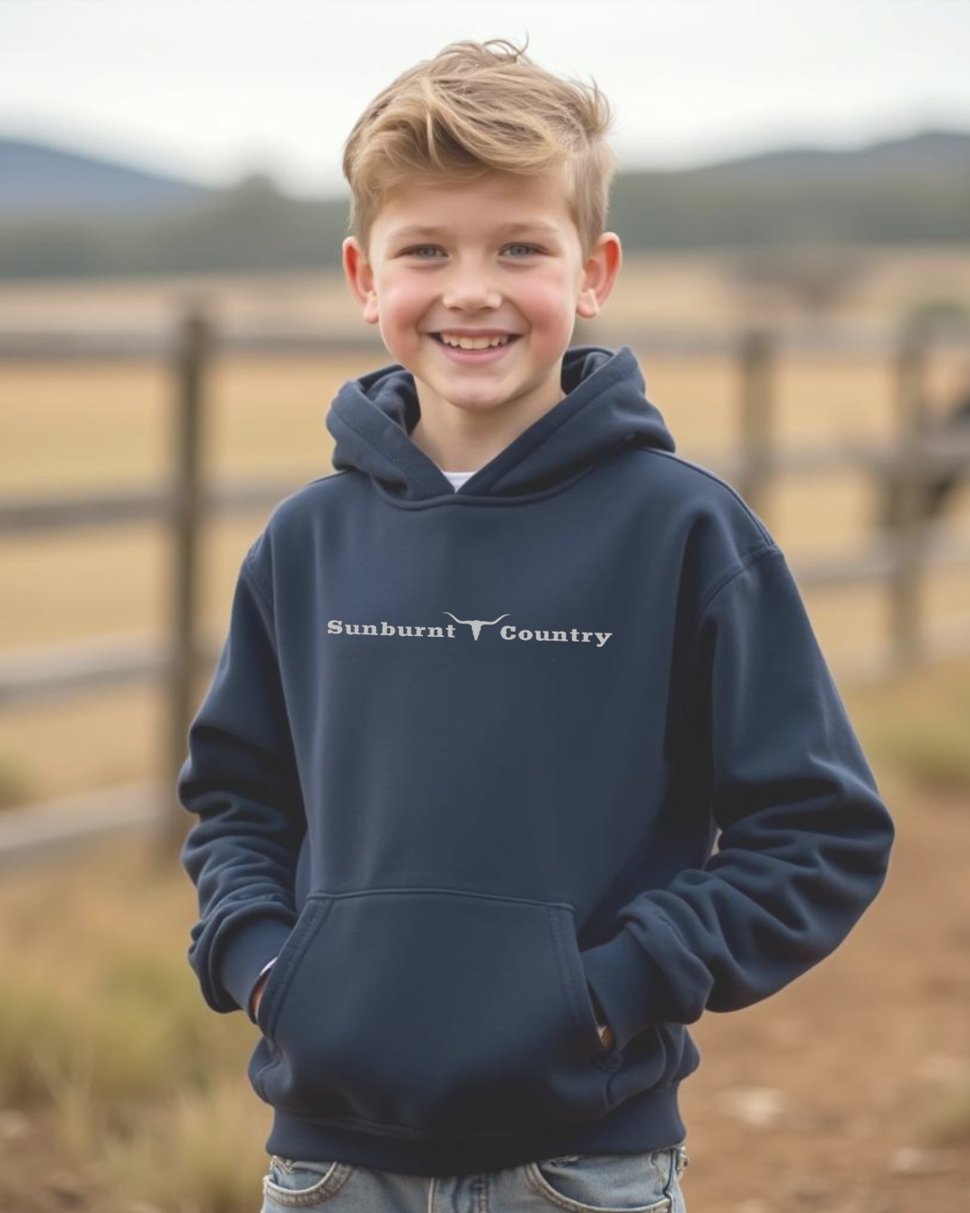 Front of a Young cowboy wearing a Navy coloured boys country western hoodie with small longhorn and text design by Sunburnt Country Clothing, Australian kids country clothing