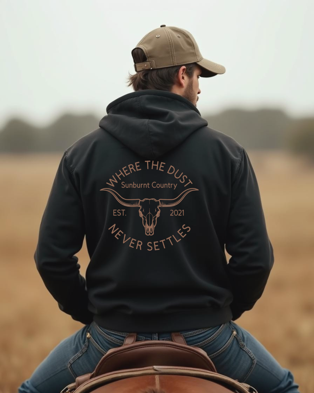 Male model wearing Sunburnt Country Clothing Black Heritage hoodie in rural setting