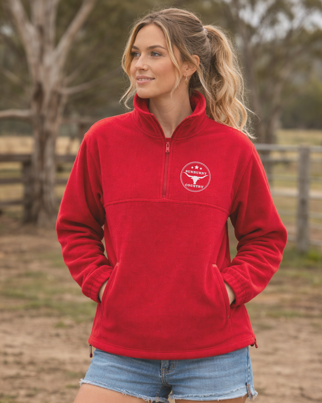 Woman wearing a Sunburnt Country Clothing cherry red polar fleece jumper with a longhorn logo in an outdoor setting