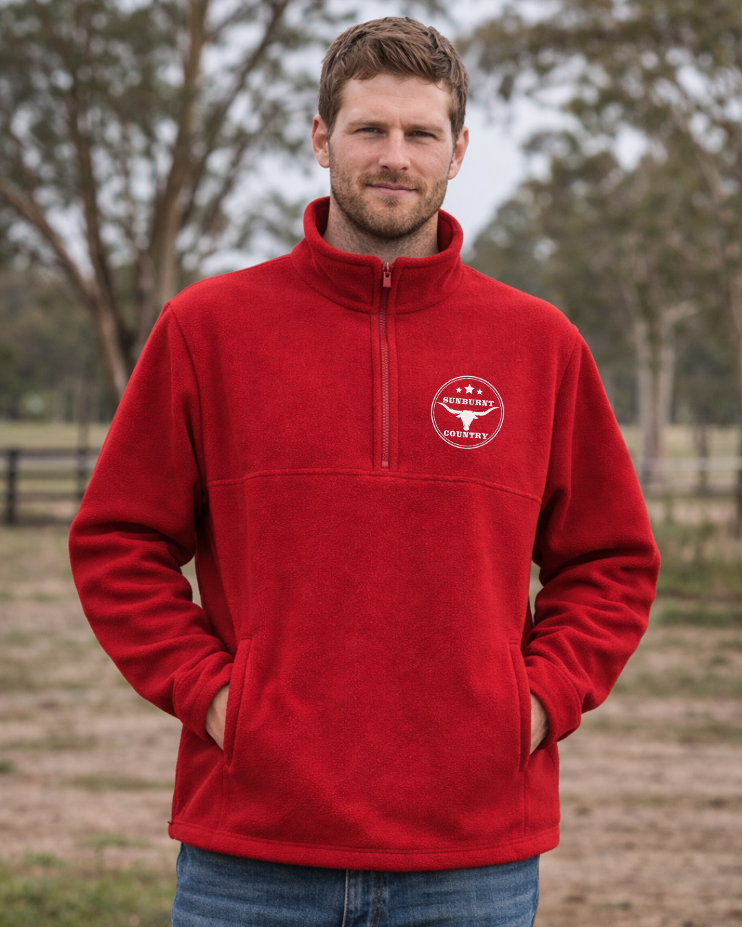 Man wearing a Sunburnt Country Clothing cherry red polar fleece jumper with a longhorn logo in an outdoor setting